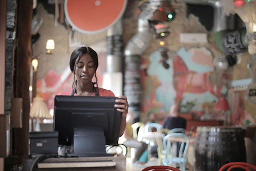 A woman using a restaurant point-of-sale system to review food delivery orders.