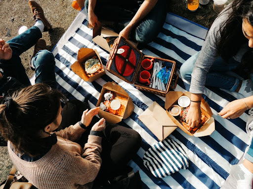 An image of a group of friends having a picnic with food ordered from a restaurant online ordering system.